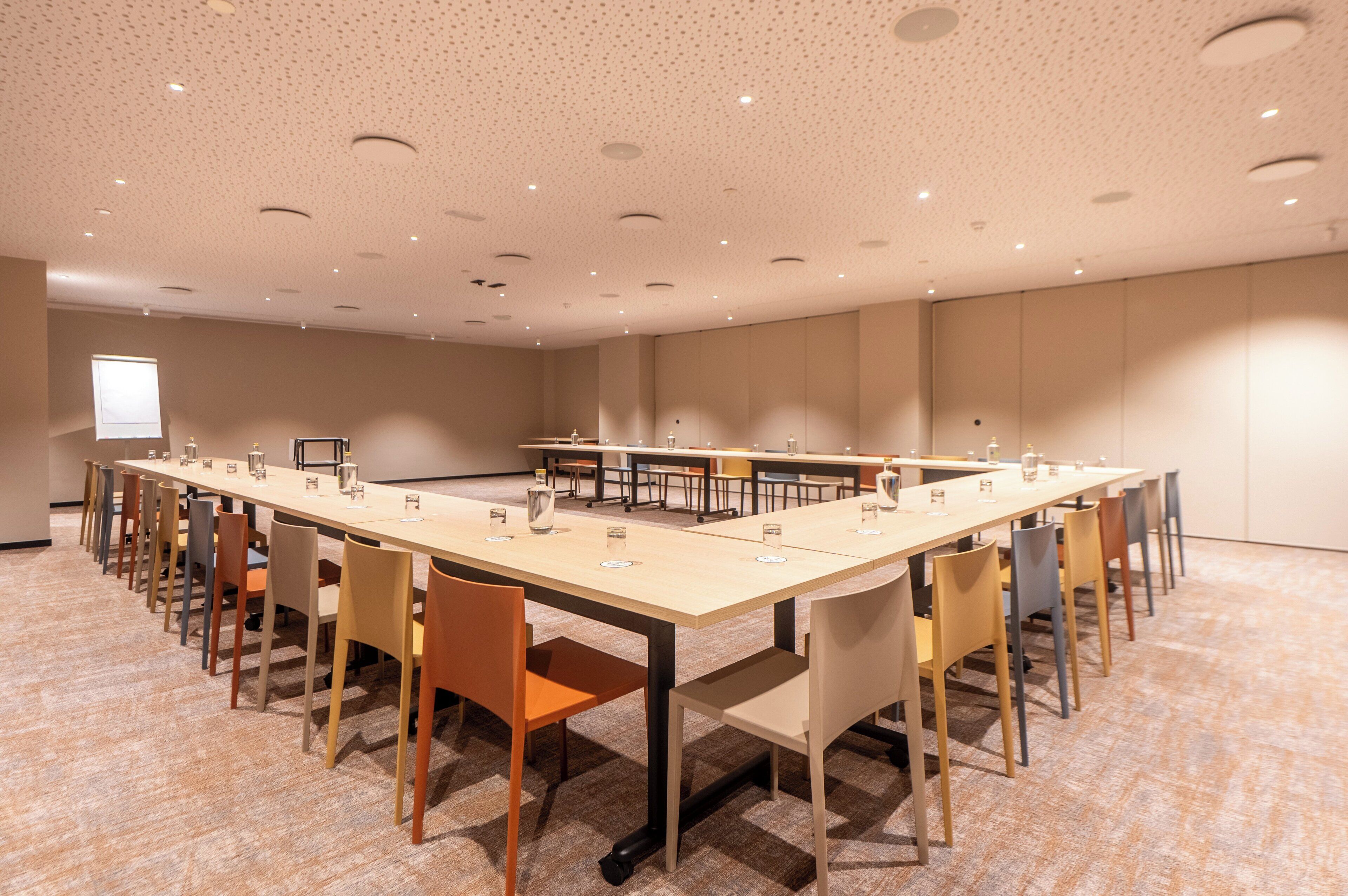 Uma sala de conferências com uma mesa comprida, várias cadeiras e uma tela de projeção.