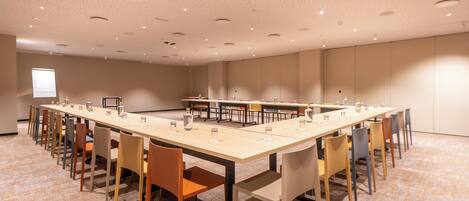 A conference room with a long table, multiple chairs, and a projector screen.