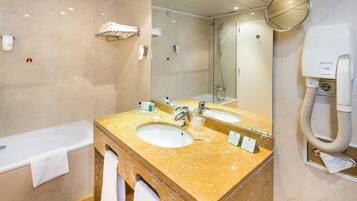 A bathroom with two sinks, a bathtub, a mirror, and a hairdryer.