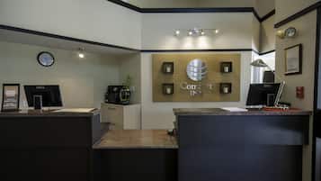 A reception desk with a clock, a Dell computer, and a sign that reads "Comfort Inn".
