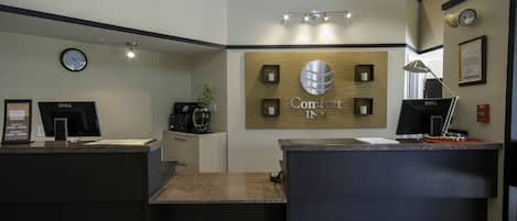 Una reception con una sveglia, un computer Dell e un cartello con scritto 'Comfort Inn'.