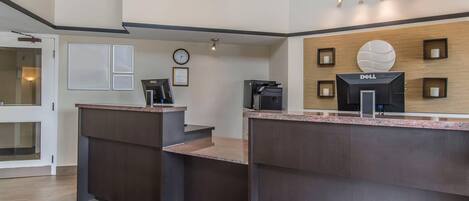 A reception area with a desk, a clock, framed certificates, and a Dell logo on the wall.