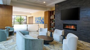 A modern lounge area with sofas, a fireplace, and a large flat-screen TV. - Detroit Marriott Troy (Troy)