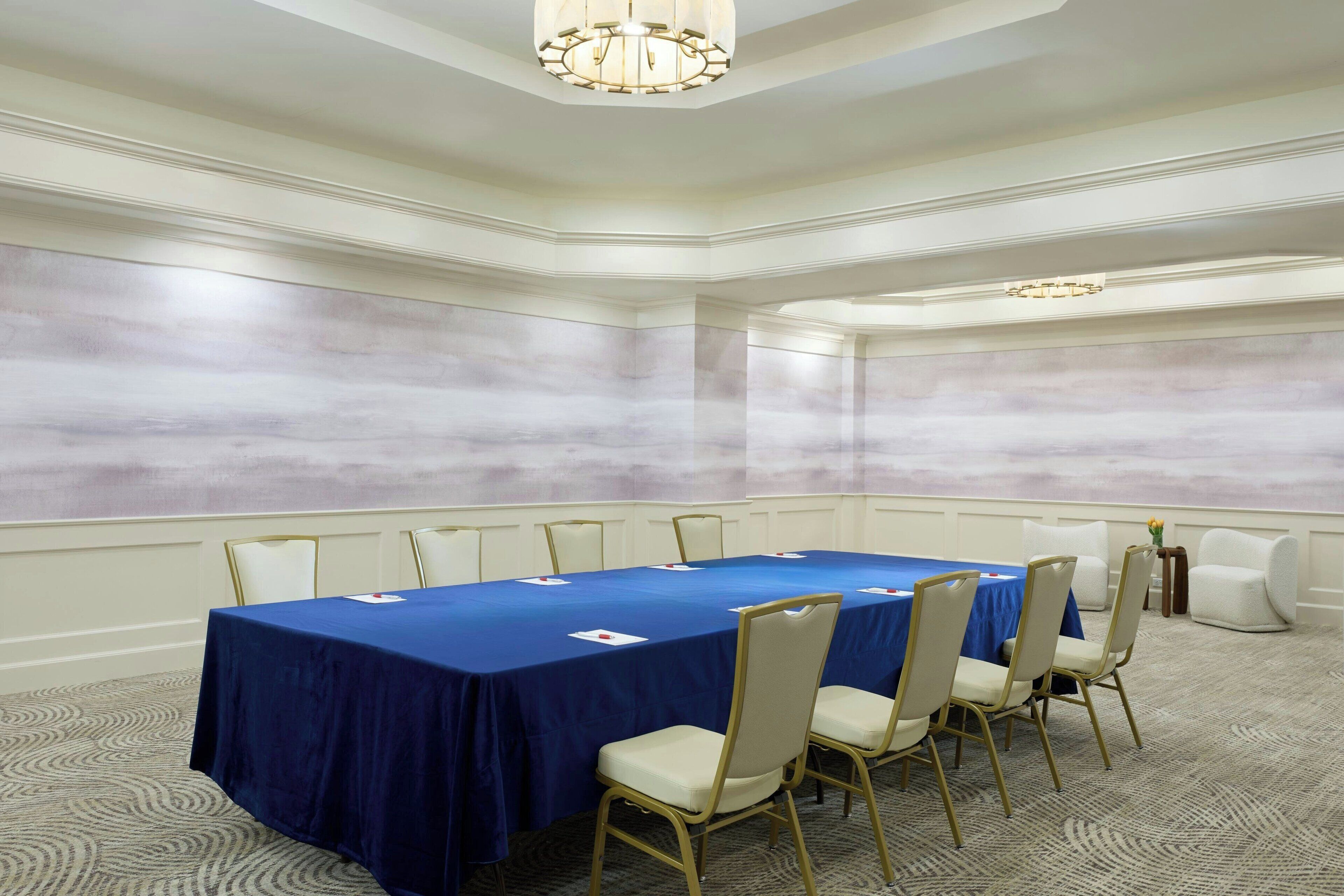 A conference room with a long table, chairs, and a carpeted floor.