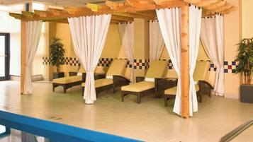A poolside area with lounge chairs, a wooden pergola, and a tiled floor.