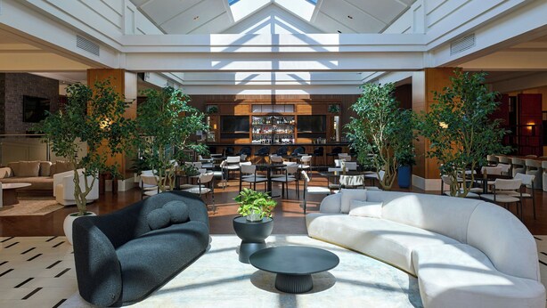 A spacious lobby with modern furniture, a bar area, and large windows allowing natural light. - Detroit Marriott Troy (Troy)