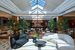 A spacious lobby with modern furniture, a bar area, and large windows allowing natural light. - Detroit Marriott Troy (Troy)