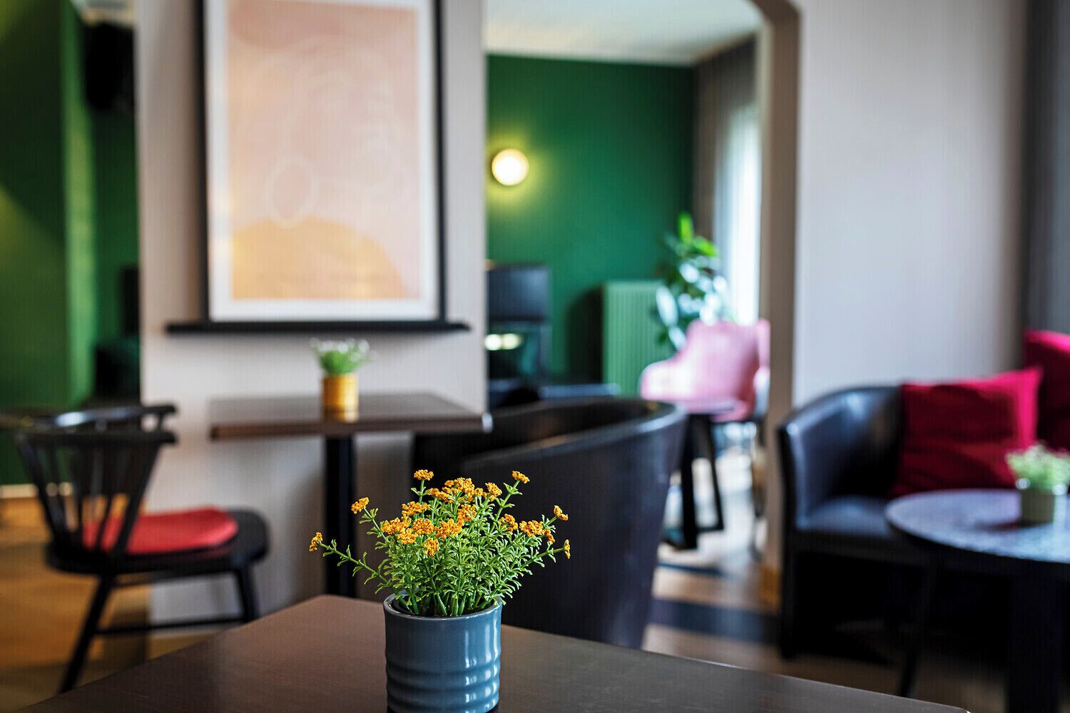 Ein modernes Interieur mit einer Sitzecke, einem Tisch mit Blumenvase und einer Wand in Grünton.