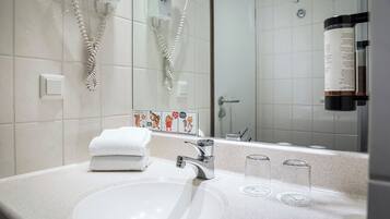 Ein Badezimmer mit einem weißen Waschbecken, einem Spiegel und einem Handtuchhalter.