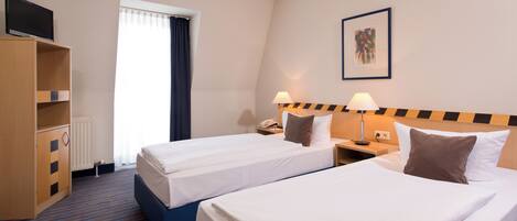 A hotel room with two beds, a TV on a stand, a desk with a lamp, and a painting on the wall.