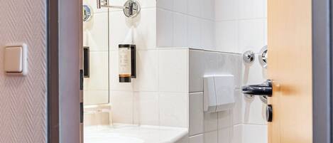 Un baño moderno con un lavabo, espejo y retrete blancos.