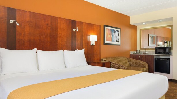 A hotel room with a large bed, a small desk, a chair, a microwave, and a sink. - Radisson Hotel Akron/Fairlawn (Akron)