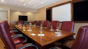 A conference room with a long wooden table, leather chairs, and a projector screen. - Radisson Hotel Akron/Fairlawn (Akron)