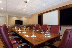 A conference room with a long wooden table, leather chairs, and a projector screen. - Radisson Hotel Akron/Fairlawn (Akron)