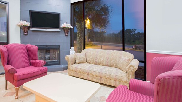 Una sala de estar con un sofá color beige, un sillón rosa y una mesa de centro blanca.