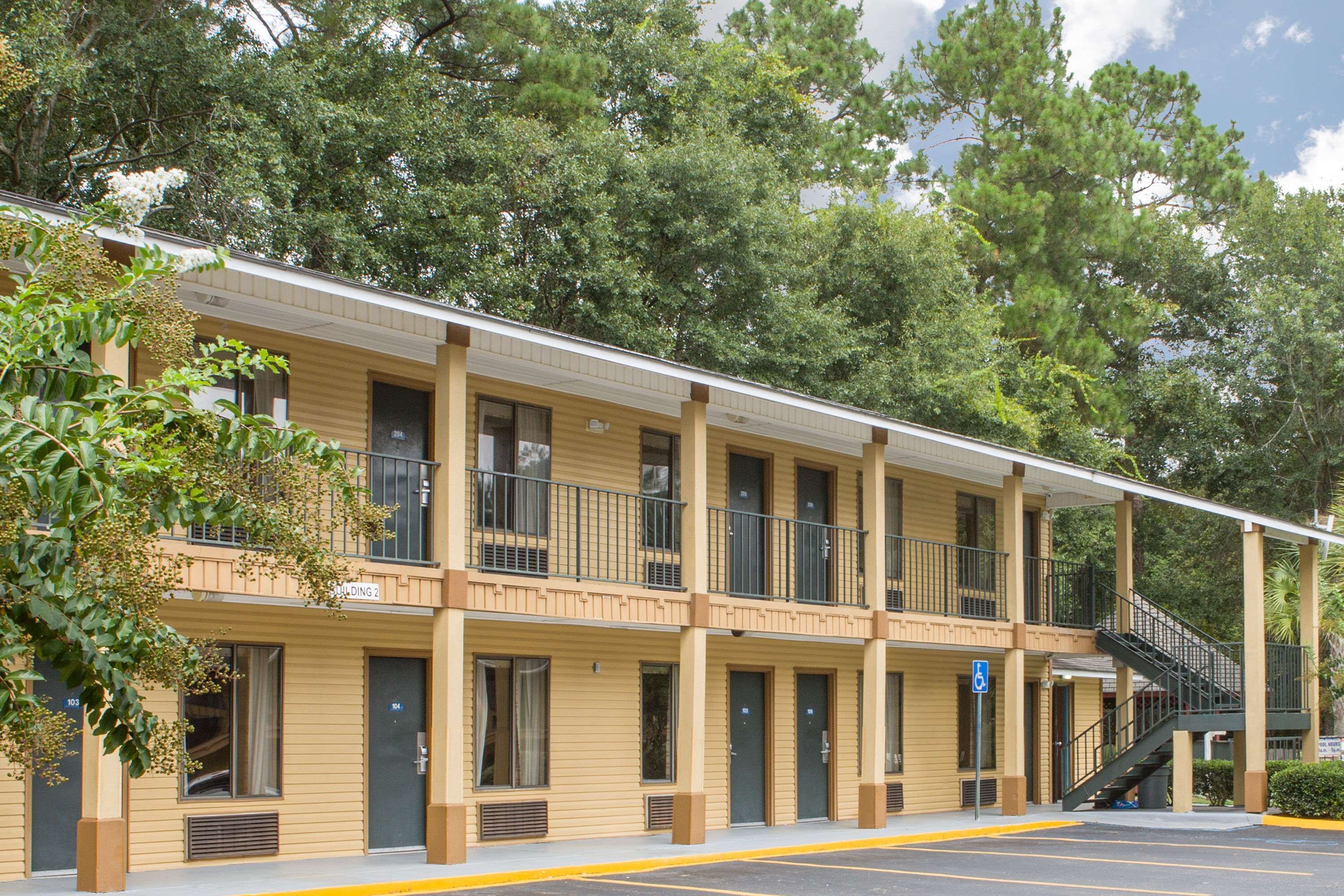 A motel with a two-story structure, multiple rooms, and a covered walkway.