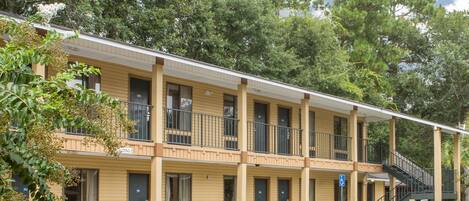 A motel with a two-story structure, multiple rooms, and a covered walkway.