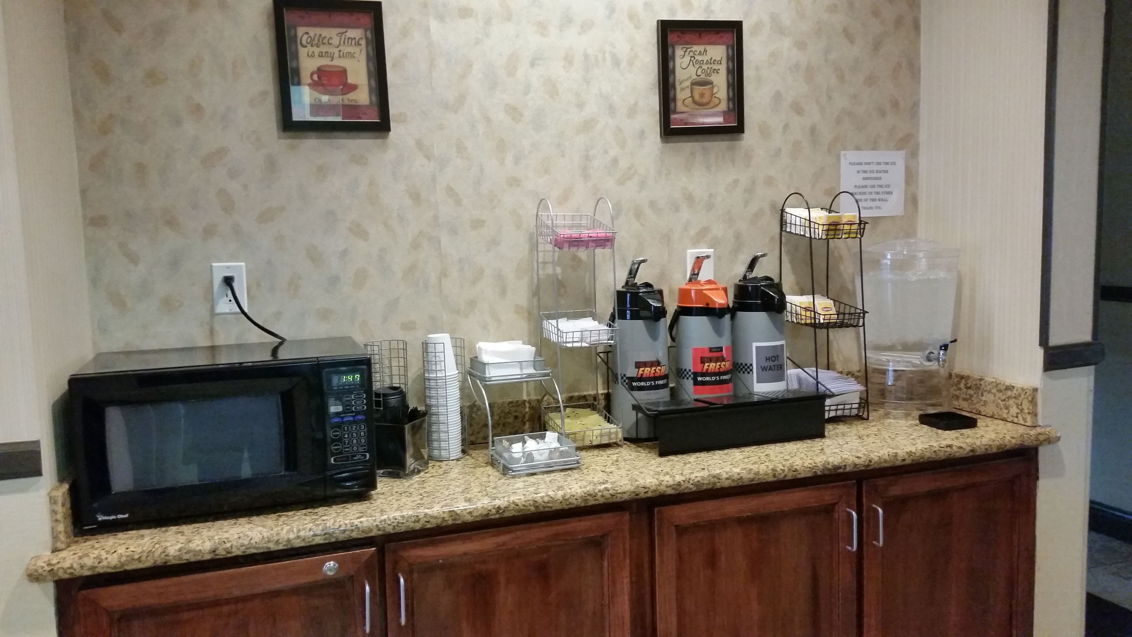 Un espace pour le petit-déjeuner à l ’hôtel, équipé d’un four à micro-ondes, de machines à café et d’un distributeur d’eau, le tout installé sur un comptoir en granit.