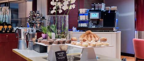 A bakery display with pastries and a coffee machine in the background.