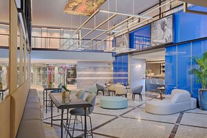 Un'ampia hall con zone relax, una scala e una grande parete blu con una scultura.