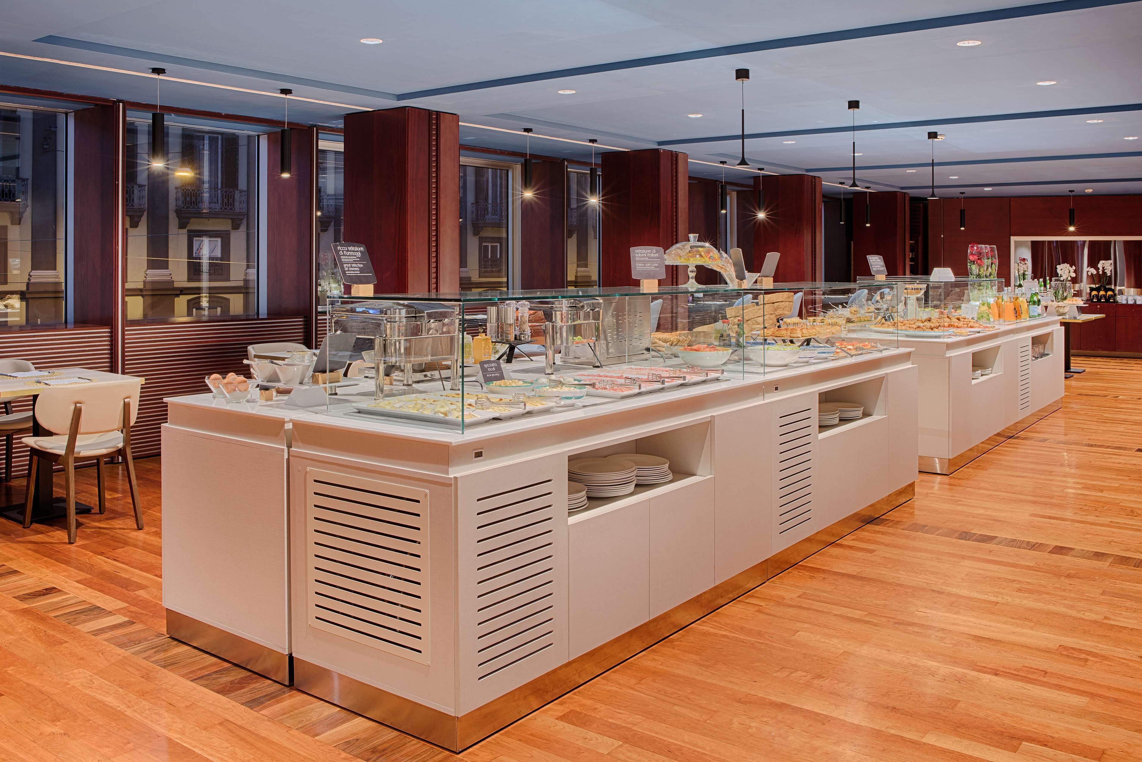 Een ontbijtbuffet met een glazen vitrine, witte kasten en een houten vloer.