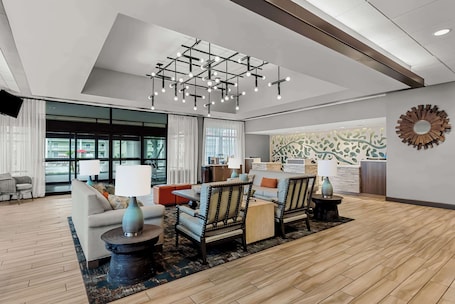 A modern hotel lobby with a seating area, a chandelier, and a decorative wall.. Best Western Seaway Inn