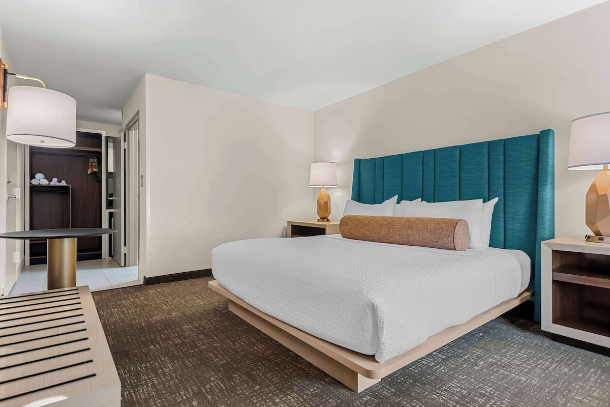 A hotel room with a large bed, bedside tables, a desk, and a wardrobe.