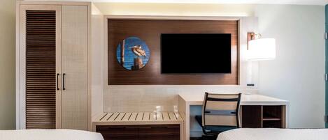 Habitación de hotel con dos camas, un escritorio, una silla, un televisor y una lámpara fijada a la pared.