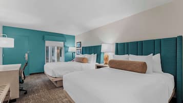 Ein Hotelzimmer mit zwei Betten, einem Schreibtisch und einem Stuhl.