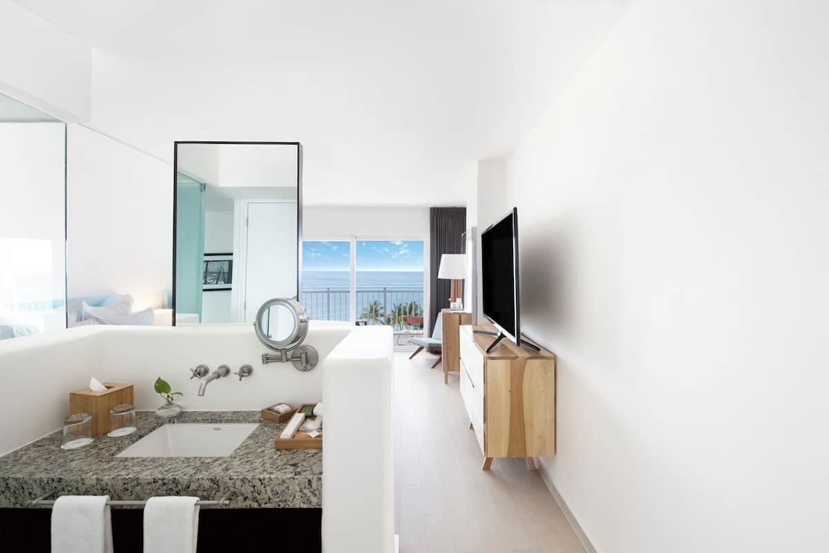 A modern bathroom with a large bathtub, a sink, and a mirror.