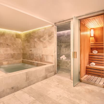 A modern bathroom with a freestanding bathtub, a wooden sauna, and a large mirror.