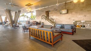 A spacious lobby with a modern design, featuring a large wooden bench, a sofa, and a staircase leading to upper levels. - Fiesta Americana Cozumel All Inclusive (Cozumel)
