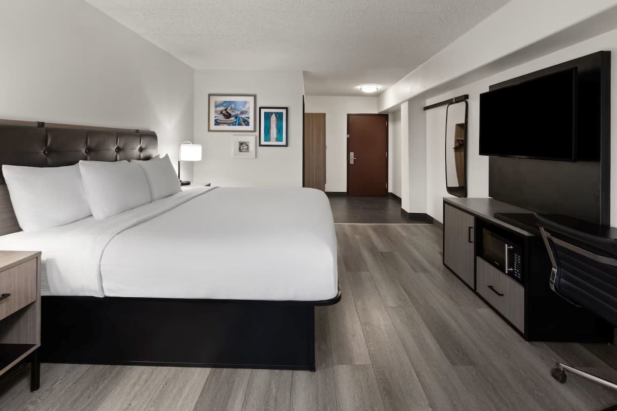 A hotel room with a large bed, a TV, a desk, and a wardrobe.