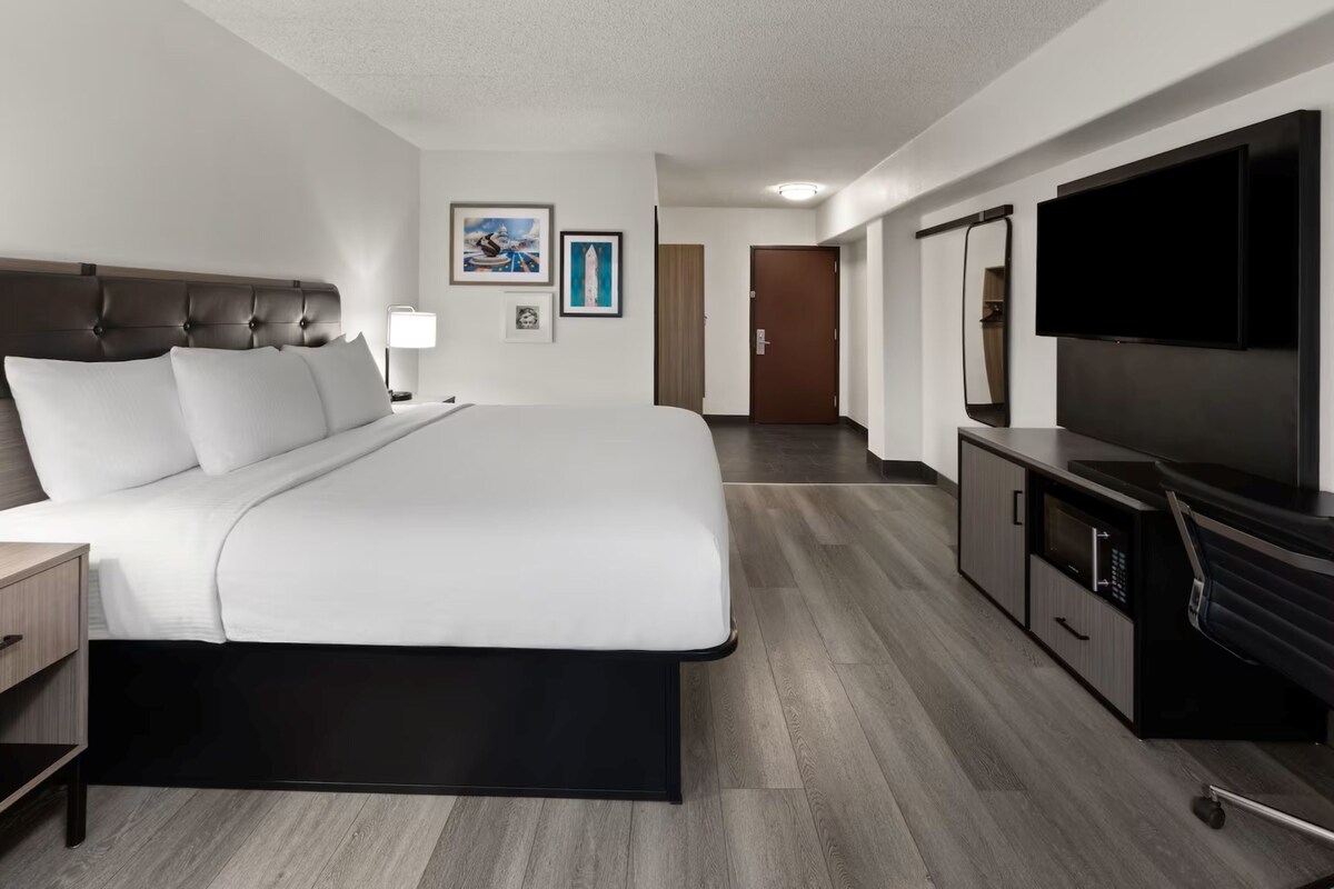 A hotel room with a large bed, a TV, a desk, and a wardrobe.