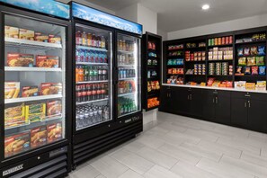 A refrigerated display with various food items and beverages, a vending machine, and shelves stocked with snacks and drinks. - Holiday Inn Express And Suites Washington Dc Noma by IHG (Washington)
