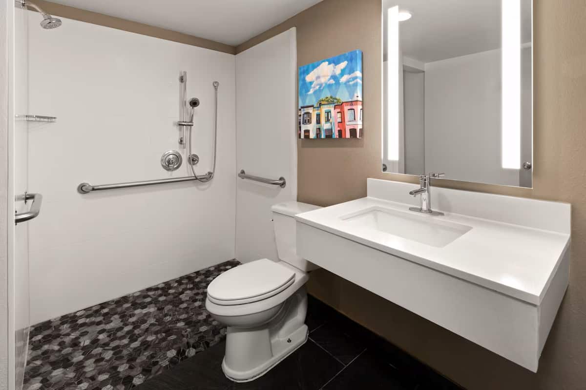 A bathroom with a shower, toilet, sink, and a mirror.
