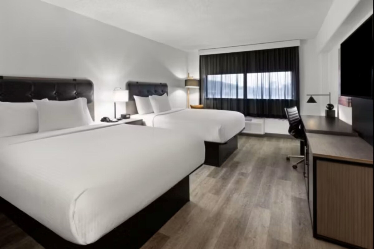 A modern hotel room with a large bed, a desk, and a chair.