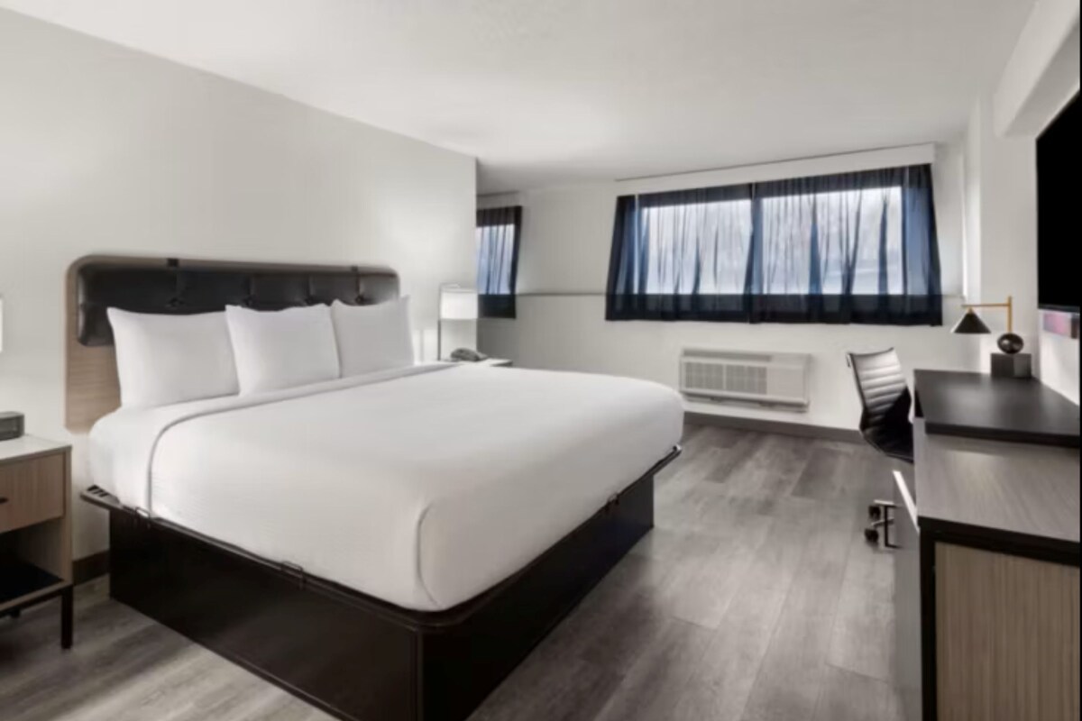 A modern hotel room with a large bed, a desk, and a chair.
