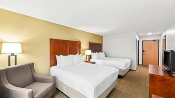 A hotel room with two beds, a sofa, a TV, and a desk.