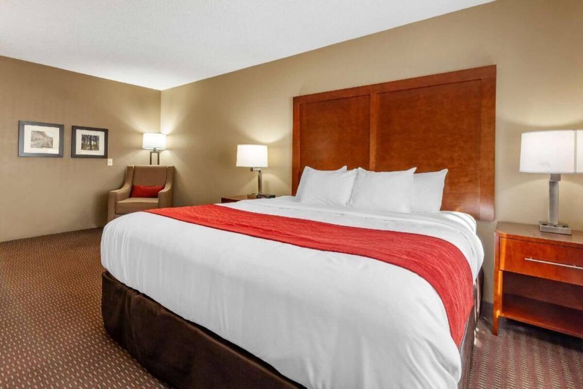 A hotel room with a large bed, two bedside tables, a chair, and framed pictures on the wall.
