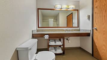 Un baño con inodoro, lavamanos, espejo y toallero.