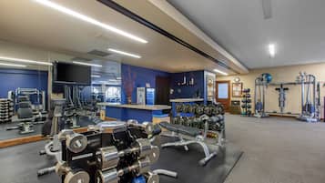 Un gimnasio con equipo de ejercicio, un espejo y una pared azul.