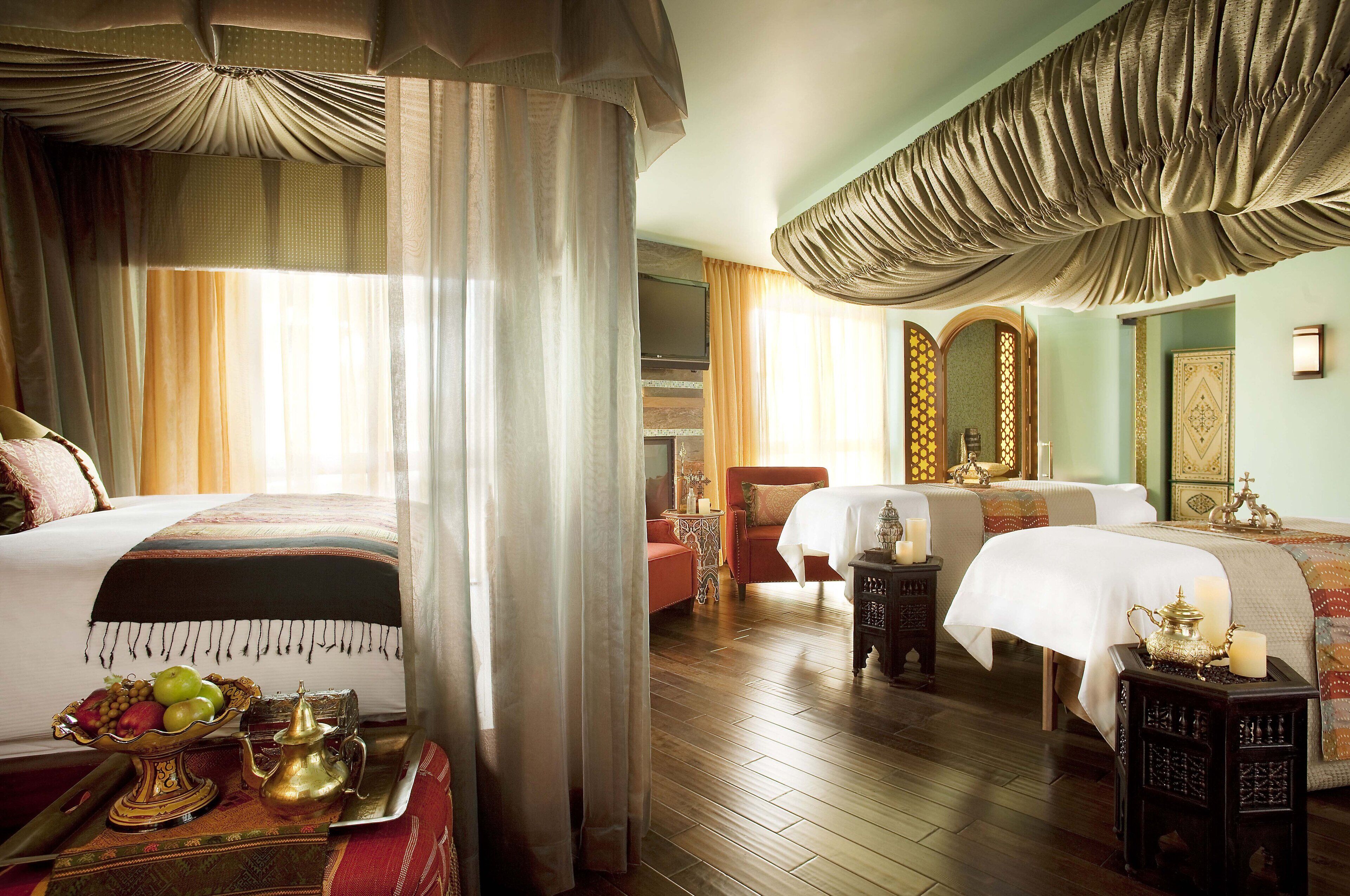 A hotel room with two beds, a sitting area, and a television.