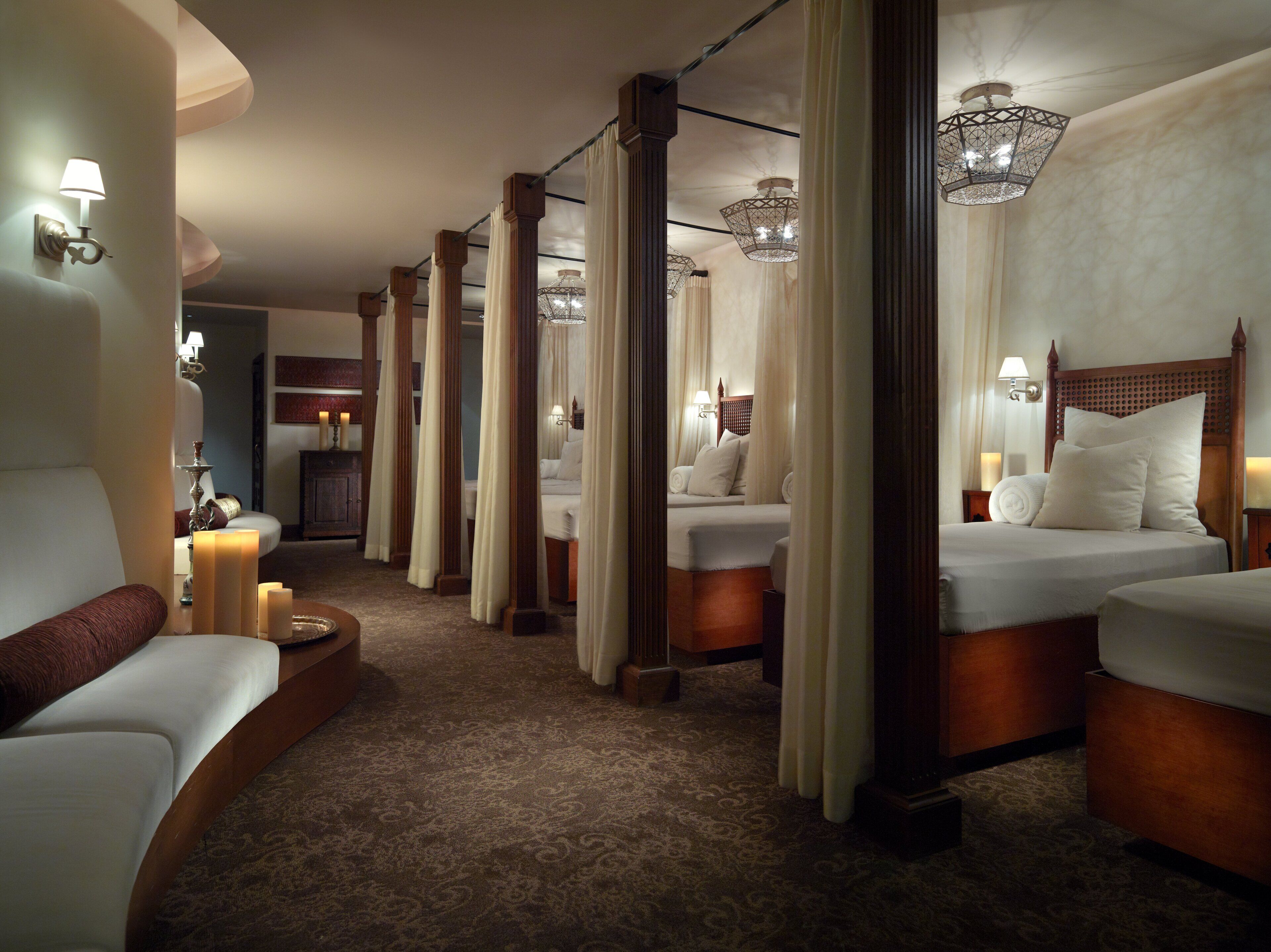 A hotel room with a large bed, a smaller bed, a sofa, and a nightstand with a lamp.