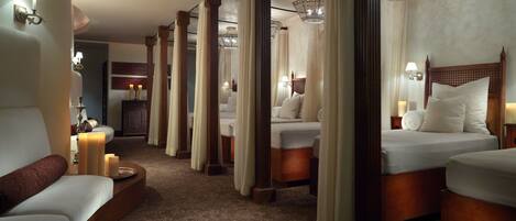 A hotel room with a large bed, a smaller bed, a sofa, and a nightstand with a lamp.