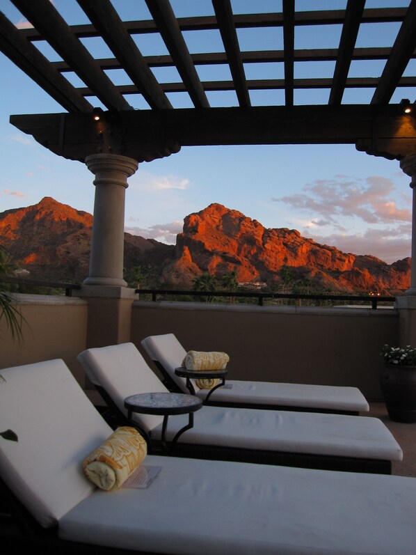 Terraza en la azotea con sillones de descanso y un pérgola, con vistas a un paisaje montañoso.