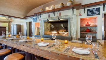 A bar area with a long counter, stools, and a menu board listing tapas.
