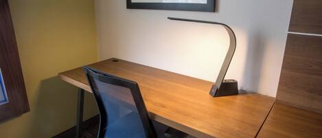 A modern office desk with a chair, a desk lamp, and a framed picture on the wall.