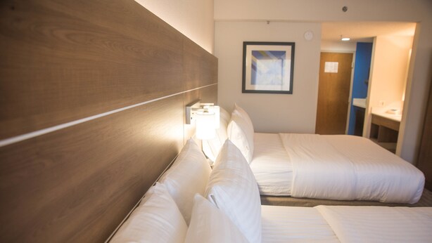 A hotel room with two beds, a wooden headboard, a nightstand with a lamp, and a framed picture on the wall. - Holiday Inn Express Easton by IHG (Easton)