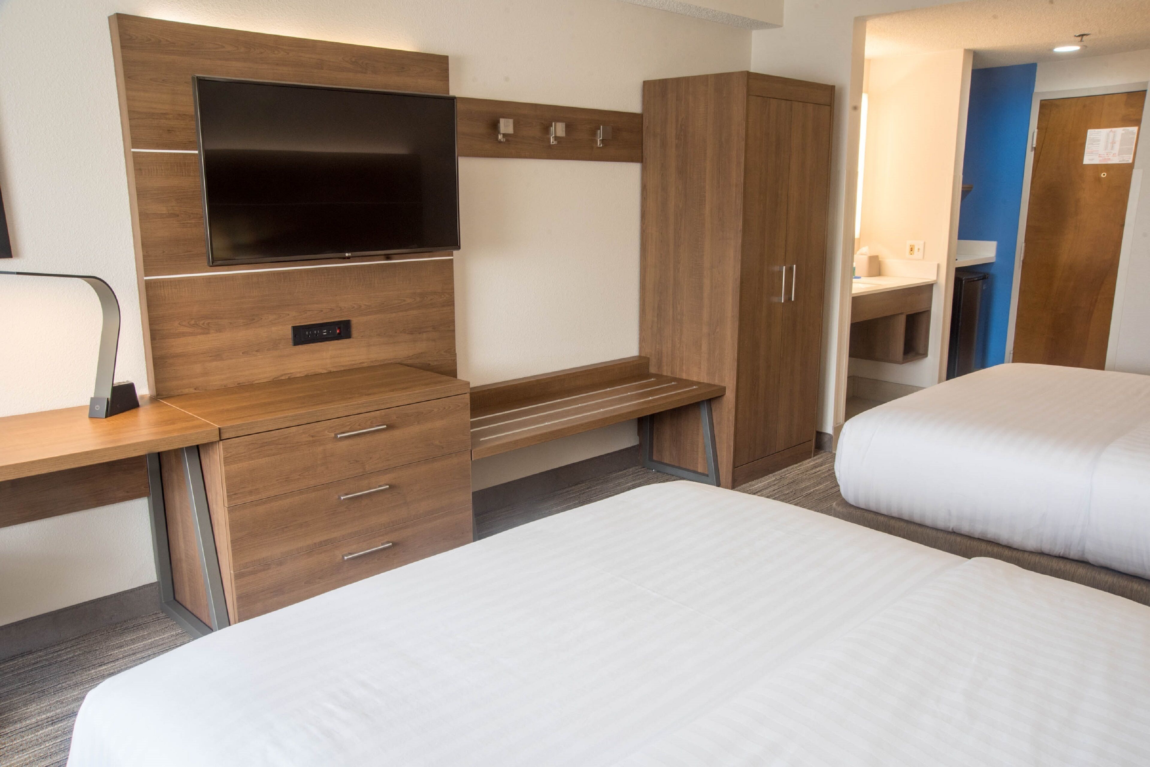 Una habitación de hotel con cama, escritorio, televisor y armario.